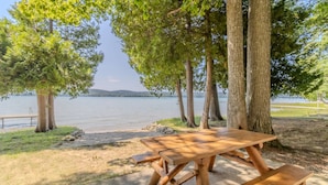 Una mesa de picnic de madera con bancos, rodeada de árboles y un lago.