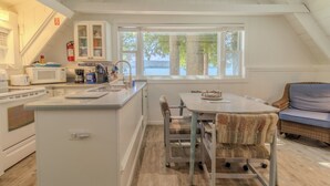 Una cocina con una isla central, armarios blancos y vistas al exterior.