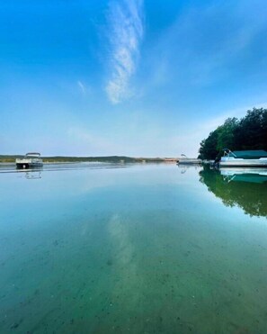 A calm body of water with boats and a tree on the right. - Gather and Relax on Little Glen Lake at Blue Haven (Empire)