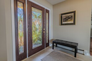Ein Korridor mit einer Bank, einem gerahmten Bild an der Wand und einer Tür mit farbigen Glasfeldern.