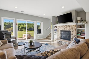 A living room with a fireplace, a television, and a bookshelf. - Spacious Private home for 14 at Blue Valley (Traverse City)