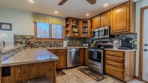 A kitchen with wooden cabinets, stainless steel appliances, and a tiled backsplash. - Ideal Suttons Bay Retreat at Broadway Base Camp (Suttons Bay)