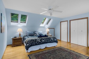 A bedroom with a bed, two bedside tables, a ceiling fan, and a large window. - Ideal Suttons Bay Retreat at Broadway Base Camp (Suttons Bay)