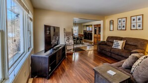 A living room with a TV, sofa, and wooden flooring. - Ideal Suttons Bay Retreat at Broadway Base Camp (Suttons Bay)