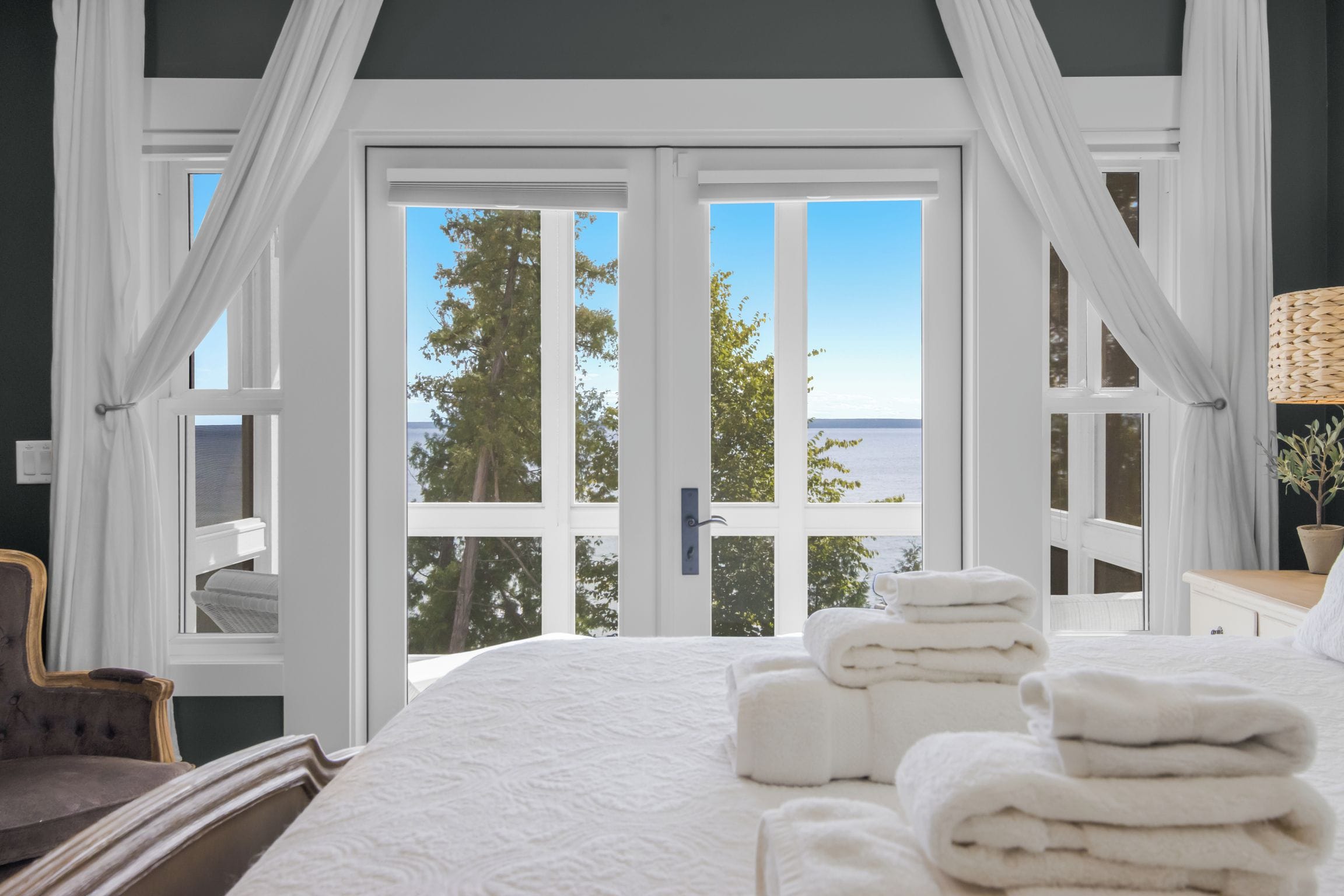 Een slaapkamer met een groot bed, uitzicht op zee en een raam met gordijnen.