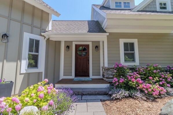 A house with a front porch, a wooden door, and a stone accent wall. - Dreamy Northern Michigan Escape, Chateau Sunrise (Suttons Bay)