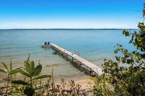 Une jetée en bois s’étendant dans une eau calme, sous un ciel dégagé.