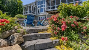 A large house with a balcony, stone steps, and a blue chair. - Dreamy Northern Michigan Escape, Chateau Sunrise (Suttons Bay)