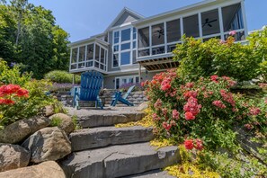 A large house with a balcony, stone steps, and a blue chair. - Dreamy Northern Michigan Escape, Chateau Sunrise (Suttons Bay)