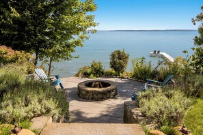 Une terrasse au bord du lac, avec un foyer, des sièges et un quai.