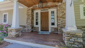 A house with a stone facade, a wooden porch, and a front door labeled "Off the Hook." - Dreamy Northern Michigan Escape, Chateau Sunrise (Suttons Bay)