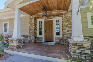 A house with a stone facade, a wooden porch, and a front door labeled "Off the Hook." - Dreamy Northern Michigan Escape, Chateau Sunrise (Suttons Bay)