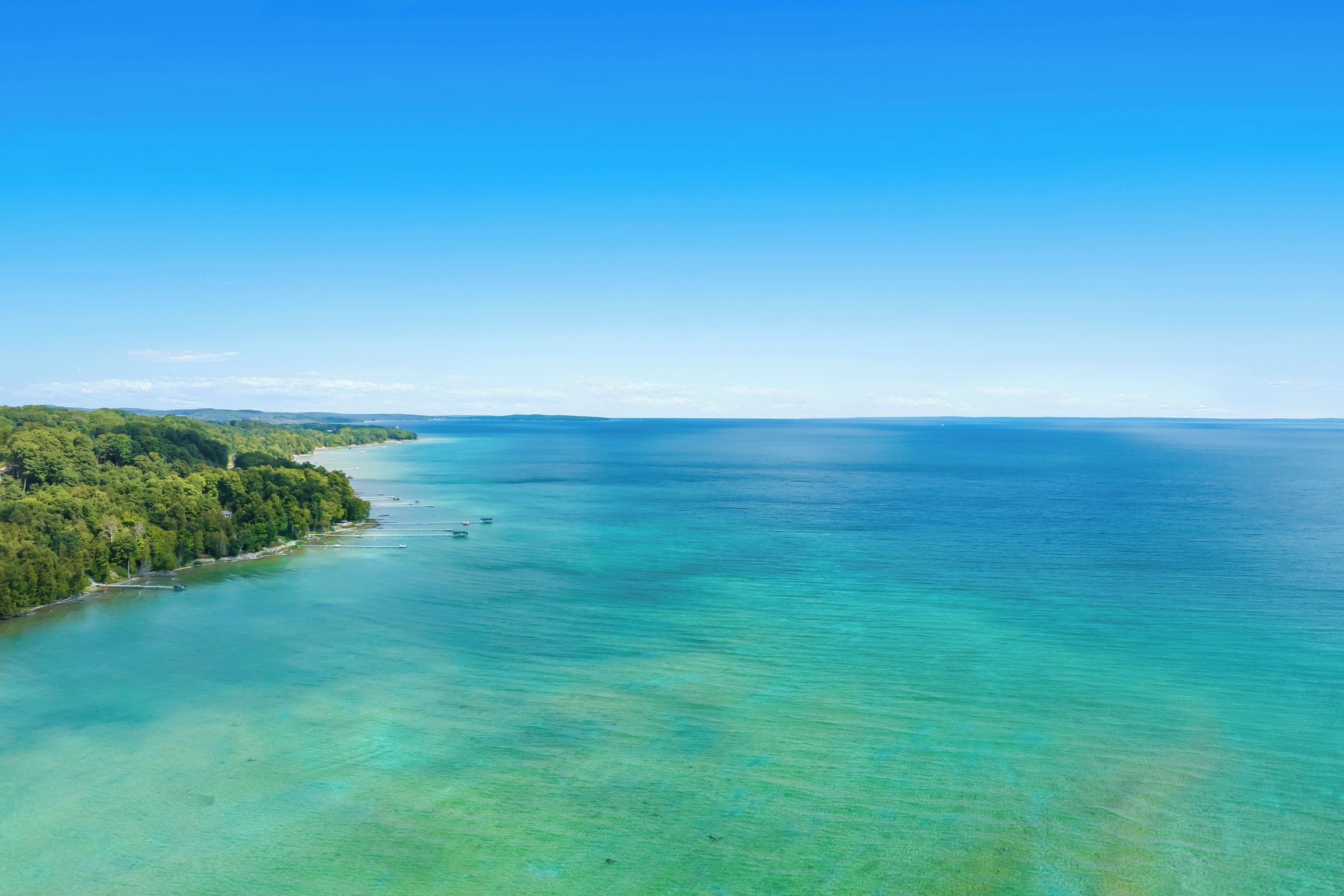 A coastal landscape with a clear view of the sea and a forested area.