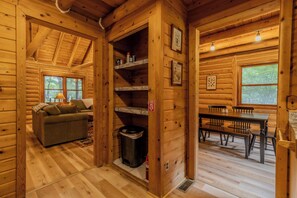Ein Blockhaus-Interieur mit einer Couch, einem Esstisch und Regalen.