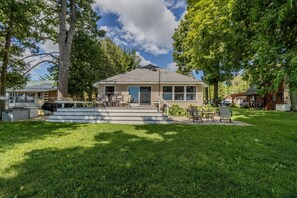 Ein eingeschossiges Haus mit Veranda, überdachter Terrasse und Rasen.