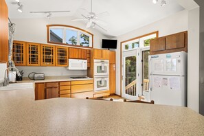 A modern kitchen with wooden cabinets, a granite countertop, a built-in microwave, an oven, and a refrigerator. - Good Harbour Prelude - Lake Michigan's Best Beach! (Lake Leelanau)