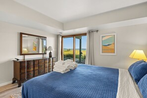 Una camera d'albergo con un letto grande, una cassettiera, uno specchio e vista sull'esterno.