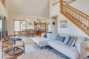 Ein geräumiges Wohnzimmer mit einer großen Eckcouch, einem Essbereich mit Holzmöbeln und einer Küche im Hintergrund.