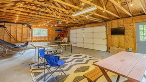 Amplo espaço interno com mesa de pingue-pongue, rede e uma cadeira dobrável.
