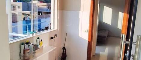 A clean, well-lit room with a large window, a mop, and a refrigerator.