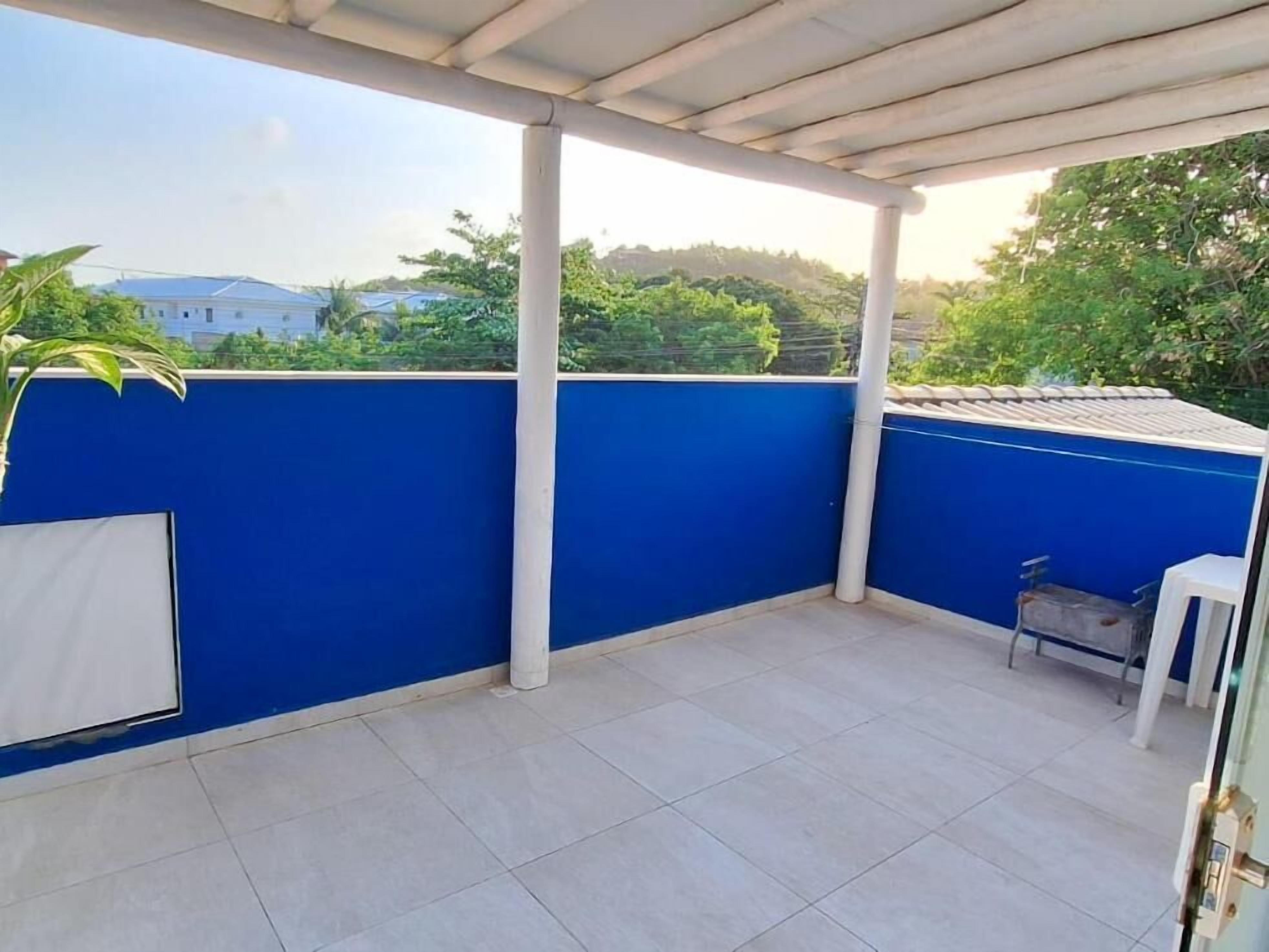 Un balcon fermé avec des murs bleus, un sol carrelé et une chaise blanche.