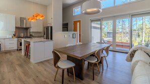 A modern kitchen with white cabinets, a wooden island, and a dining area with a large table and chairs.