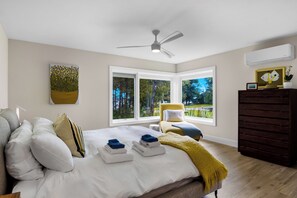 Un dormitorio con cama, una silla, cómoda y ventilador de techo.