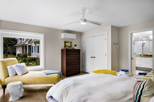 Un dormitorio con cama, una silla, armario y ventilador de techo.