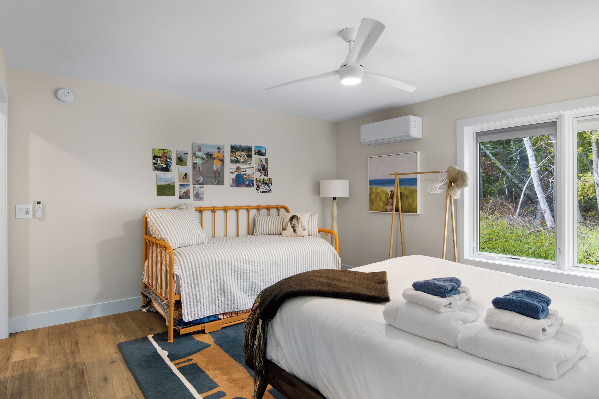 Een slaapkamer met een bed, een plafondventilator, een raam met uitzicht en wandairconditioning.