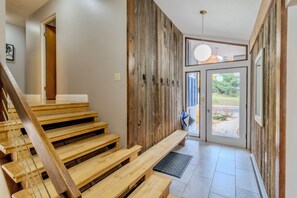 Eine Holztreppe führt zu einem Raum mit einem großen Fenster und einer Tür.