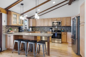 A modern kitchen with a central island, stainless steel appliances, and wooden cabinetry.