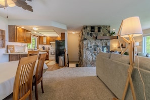 A modern kitchen with wooden cabinets, a stone accent wall, and a built-in fireplace. - Violet’s View — Where Pets & People Vacation (Suttons Bay)