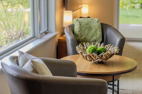 A modern living room with a leather sofa, a round wooden table, and a decorative basket with green objects.