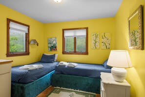 Ein Zimmer mit zwei Betten, einer Lampe und Kunstwerken an den Wänden.