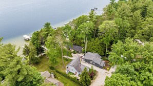 A lakeside property with a house, dock, and surrounding greenery. - Cozy Cottage on Long Lake, Your Perfect TC Getaway (Traverse City)