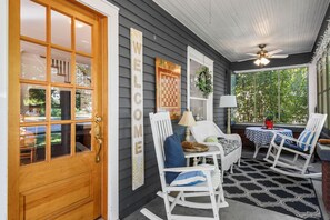 A porch with a wooden door, rocking chairs, a checkered table, and a 'WELCOME' sign. - Welcome to All-Seasons Downtown Beulah Beauty! (Beulah)