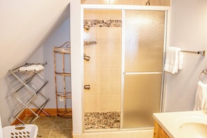 A bathroom with a glass shower door, a white sink, and a towel rack.