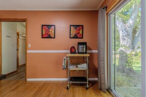 A hallway with wooden flooring, a metal cart with a kettle and a coffee maker, and a window with a view of a tree. - Halcyon House - Nearly waterfront at Long Lake! (Traverse City)