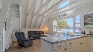 Une cuisine moderne dotée d’un grand îlot central, de meubles blancs et d’une fenêtre offrant une vue sur l’extérieur.