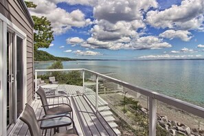 Une terrasse en bois, agréée de mobilier d’extérieur, donnant sur un lac.