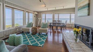 A spacious living room with large windows, a fireplace, and a dining area. - Panoramic Point - dazzling views and private beach (Traverse City)