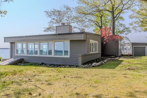 A modern house with a large windowed front section, a chimney, and a small porch area. - Panoramic Point - dazzling views and private beach (Traverse City)