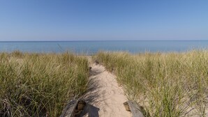 A sandy path leading to the sea, surrounded by tall grass. - Tranquil beachfront studio at Sunset Suite (Empire)