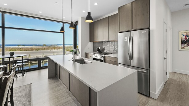 A modern kitchen with a large island, stainless steel appliances, and a view of the beach.