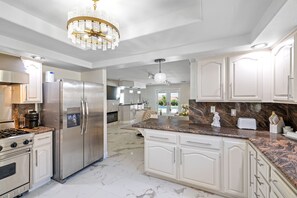 A modern kitchen with stainless steel appliances, marble countertops, and white cabinetry. - Luxe 3BR Oasis w/ Pool + Outdoor Lounge (Henderson)