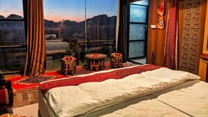 A bedroom with a large bed, a view of the mountains, and traditional decor. - Desert Sand Camp (Wadi Rum)