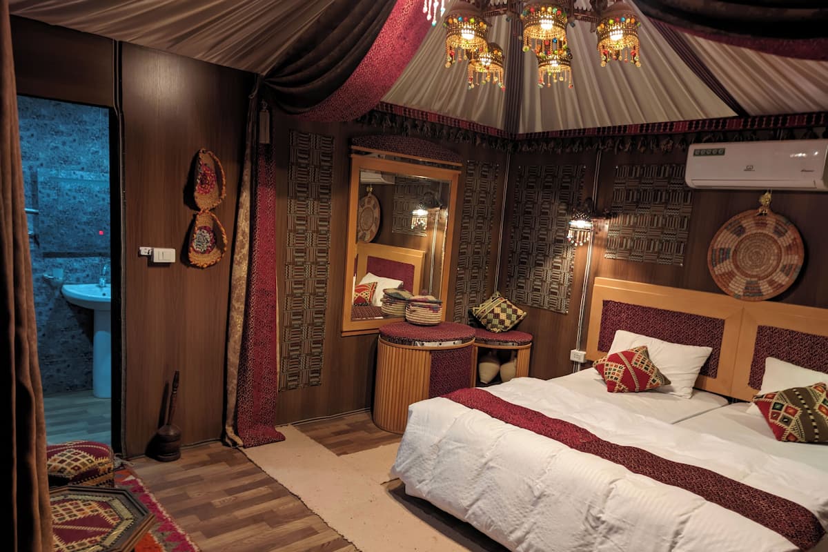 Un dormitorio con una cama grande, una mesita de noche, un espejo y un aire acondicionado instalado en la pared.