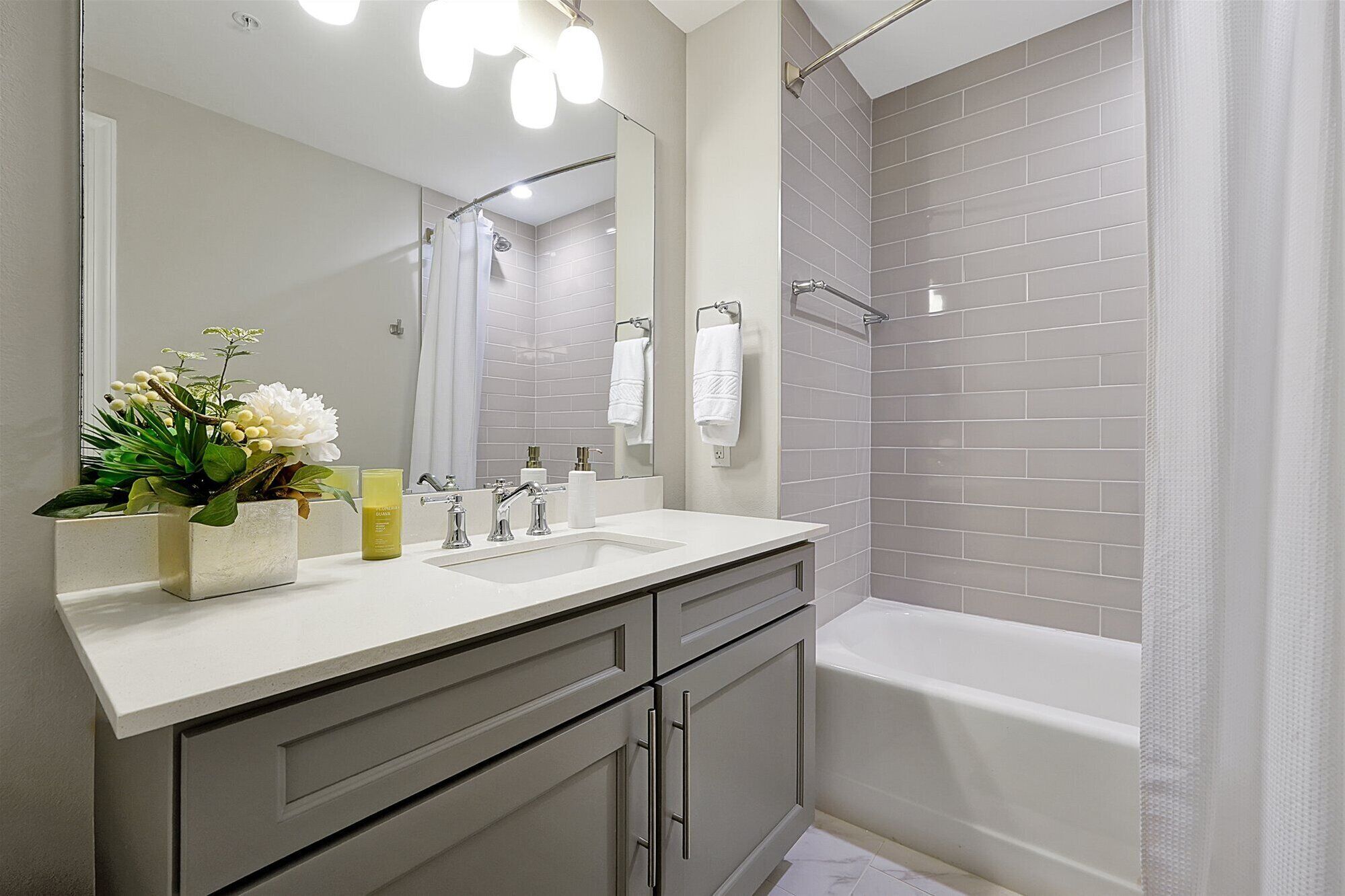 Un baño moderno con tocador blanco, un espejo grande y una bañera.