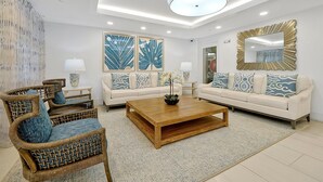 A modern living room with a sofa set, two armchairs, a coffee table, and decorative wall art.