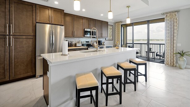 A modern kitchen with dark wood cabinets, stainless steel appliances, and a white island with bar stools.